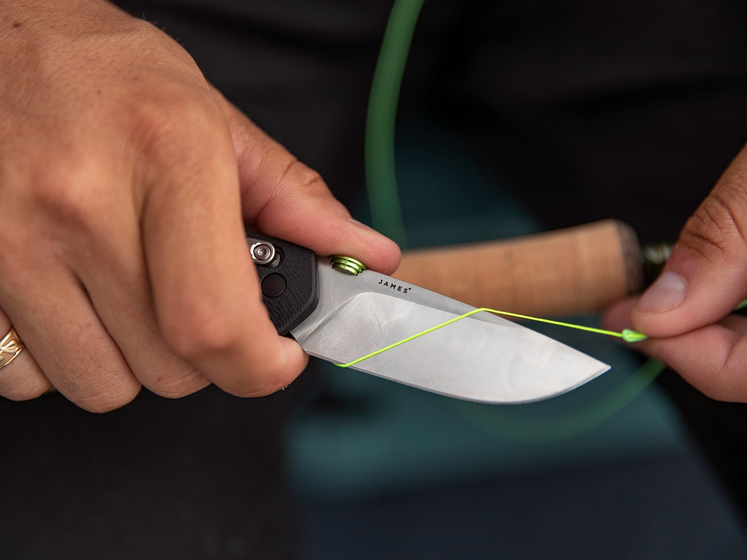 A man cutting fishing line with his Carter EDC slide lock folding pocket knife.