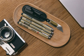 The mystery vinyl Abbey mini fixed blade knife with pens and a camera on a desk.