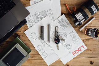 The Bolen titanium EDC twist pen with a pocket knife and a carabiner keychain on a desk.