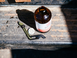 The Halifax EDC keychain multitool next to a bottle of beer on a truck's tailgate.