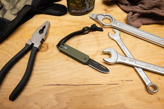 The Elko EDC keychain slip joint folding pocket knife with tools on a work bench.
