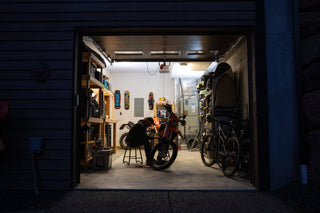 A man working on his dirt bike in the garage at night.