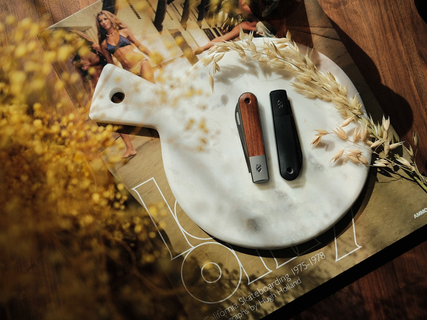 One black and one rosewood Wayland classic Barlow EDC folding slip joint pocket knife on a end table.