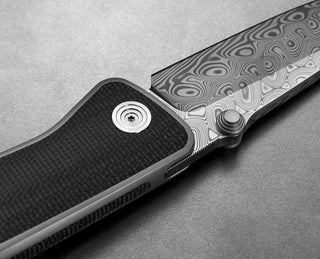 The pivot of The Barnes integral titanium EDC frame lock pocket knife with Damasteel blade and black Micarta handle.
