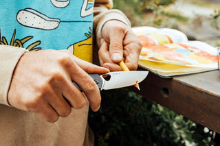 A man shaving a pencil with his Folsom liner lock folding pocket knife.