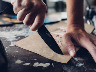 A man cutting paper with the Hell Gap fixed blade camping knife.