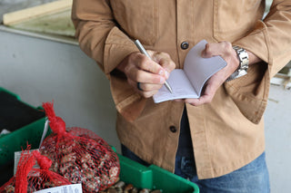 A man writing in his notebook with The Stilwell compact travel pen.