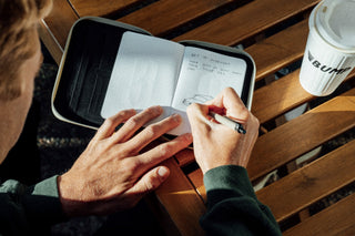A man writing in his notebook with a pen.