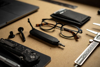 The Warrick EDC bit driver in black with everyday objects on a work bench.