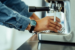 A man wearing the James x Timex GMT Automatic titanium watch making espresso.
