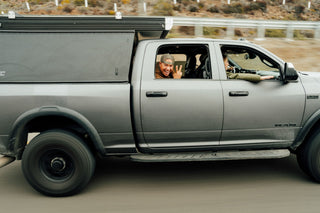 A man flashing the peace sign on from a truck on the road in Baja California.