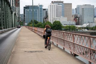 A woman riding her bike across a bridge towards Portland, Oregon.