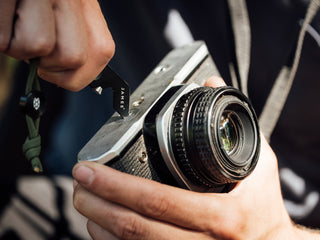A photographer adjusting his camera with The Halifax EDC keychain multitool.