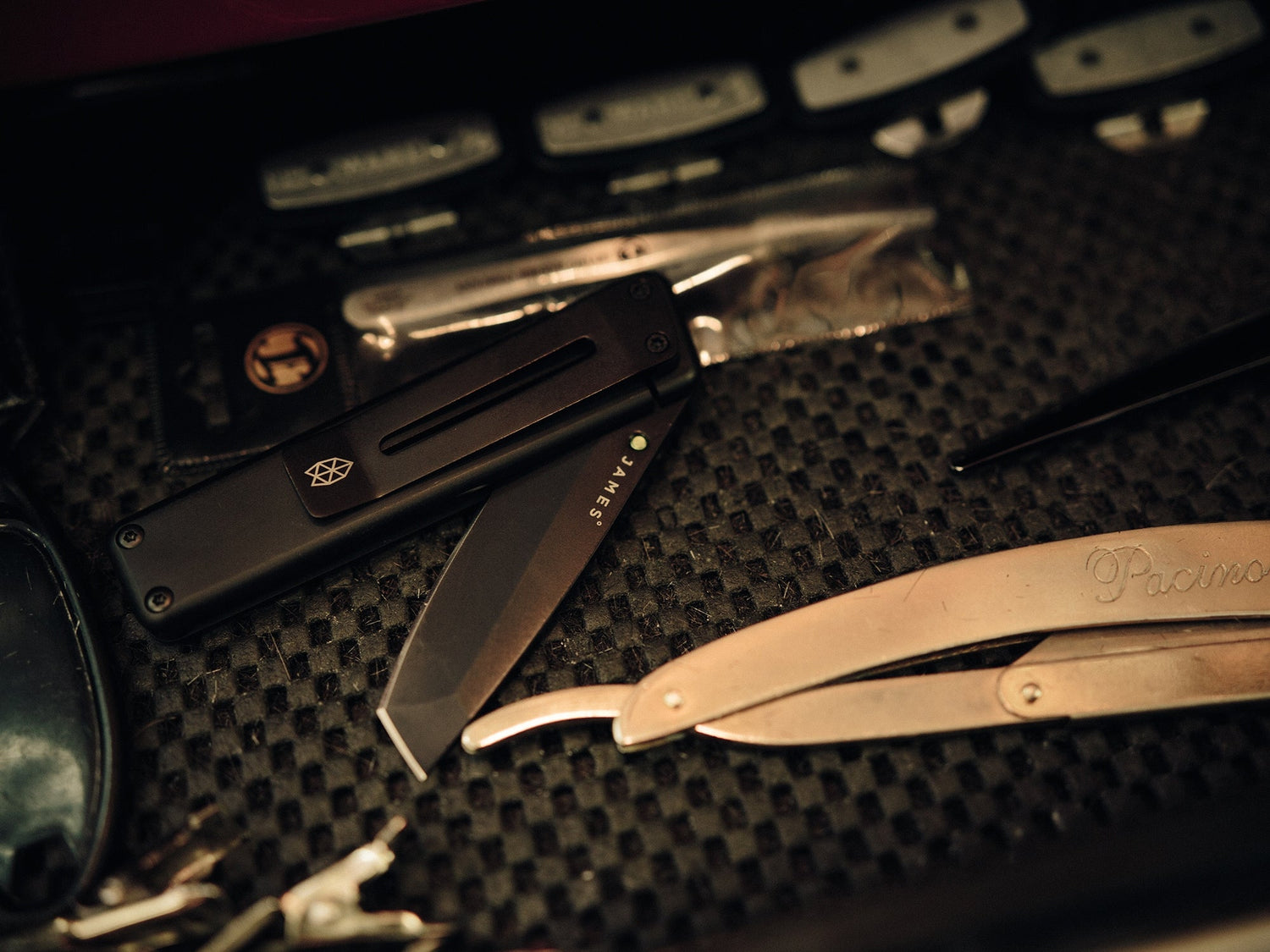 A black Chapter EDC folding frame lock pocket knife next to barber Paul Hewitt's tools.