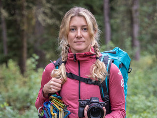 Professional rock climber and photographer Savannah Cummins with her climbing gear in the woods.