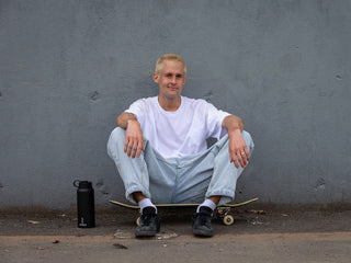Artist Sebo Walker sitting on his skateboard.